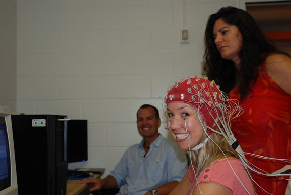 A female participant smiling towards the camera after being connected to the electrodes. 