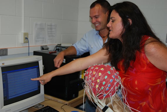 A female lab participant connected with electrodes checking the result on computer screen.