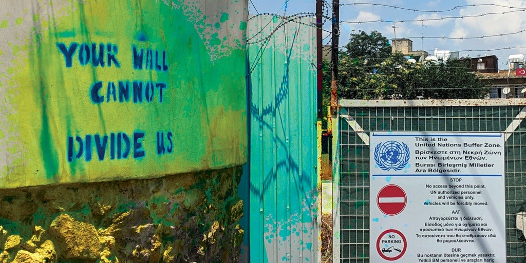 The United Nations Buffer Zone with graffiti on the wall that says "your wall cannot divide us"