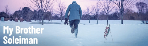 Person walking in the snow away from memorial wreath