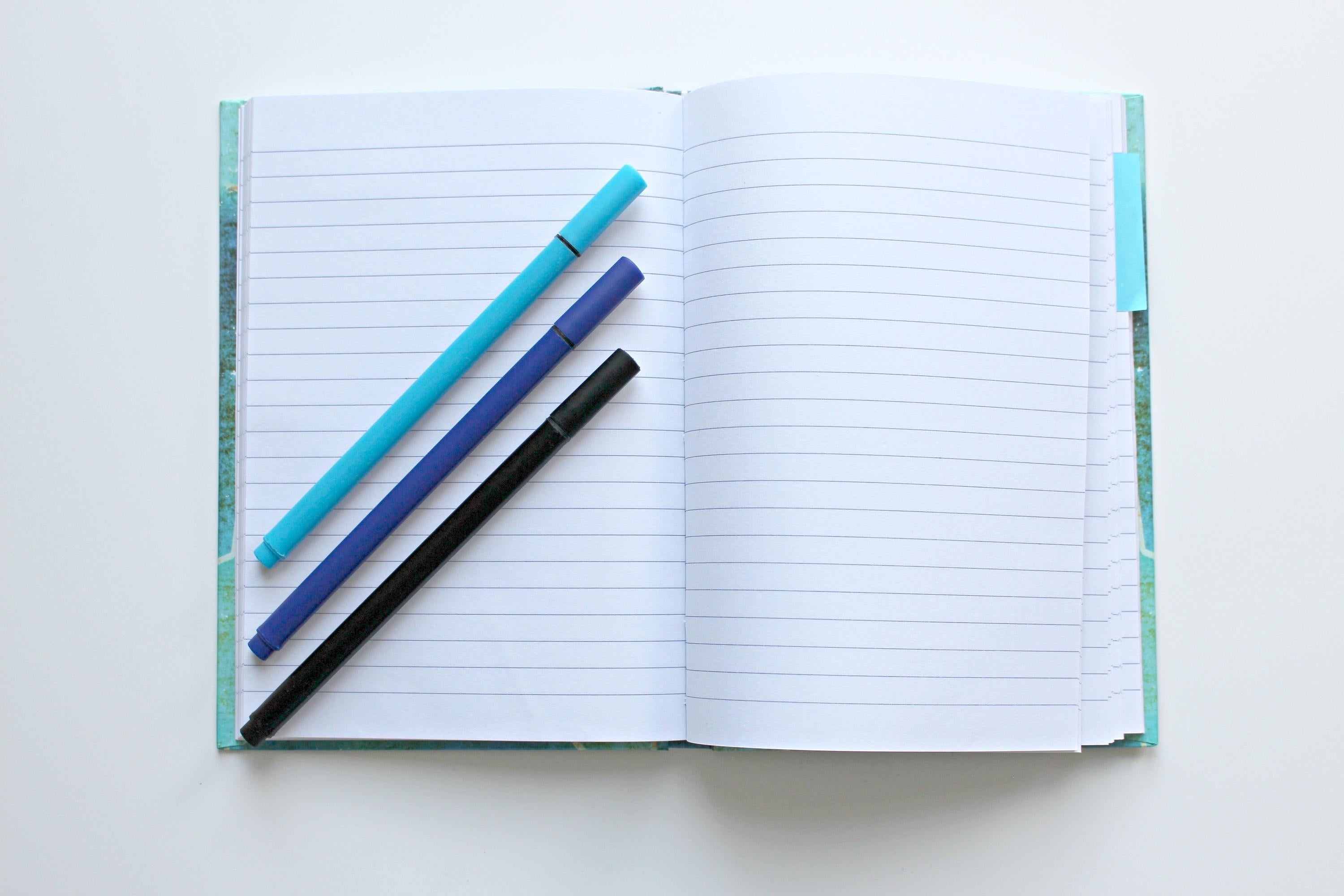Notebook with blue pens on top