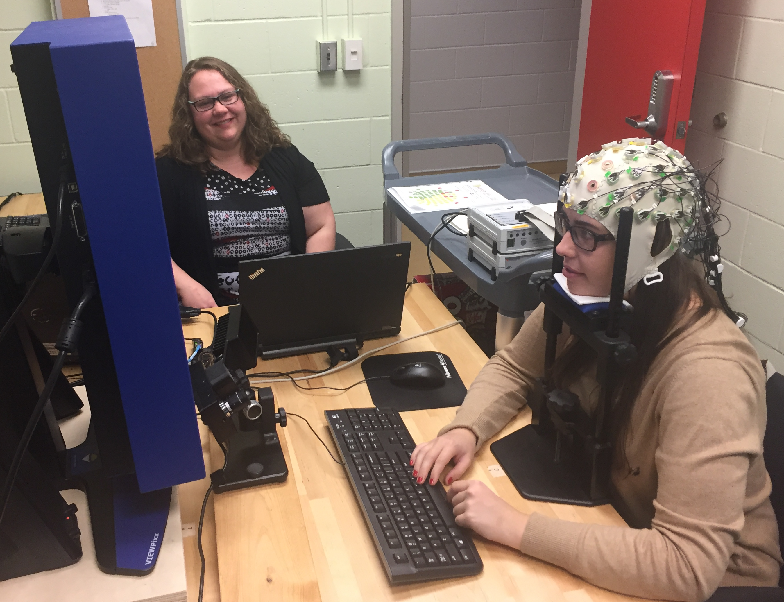 Graduate student Karisa Parkington and research assistant Karla Murtescu demonstrate an EEG and eye-tracking experiment