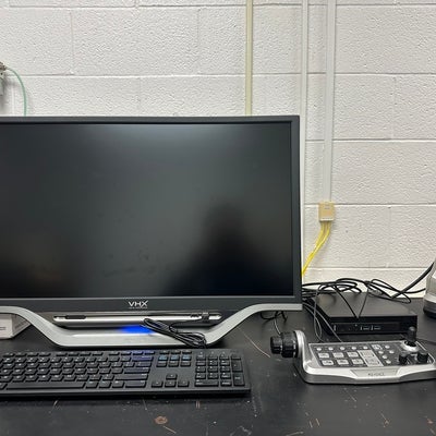 An all-in-one PC with a monitor connected to a cable box leading to an electronic microscope on the right.