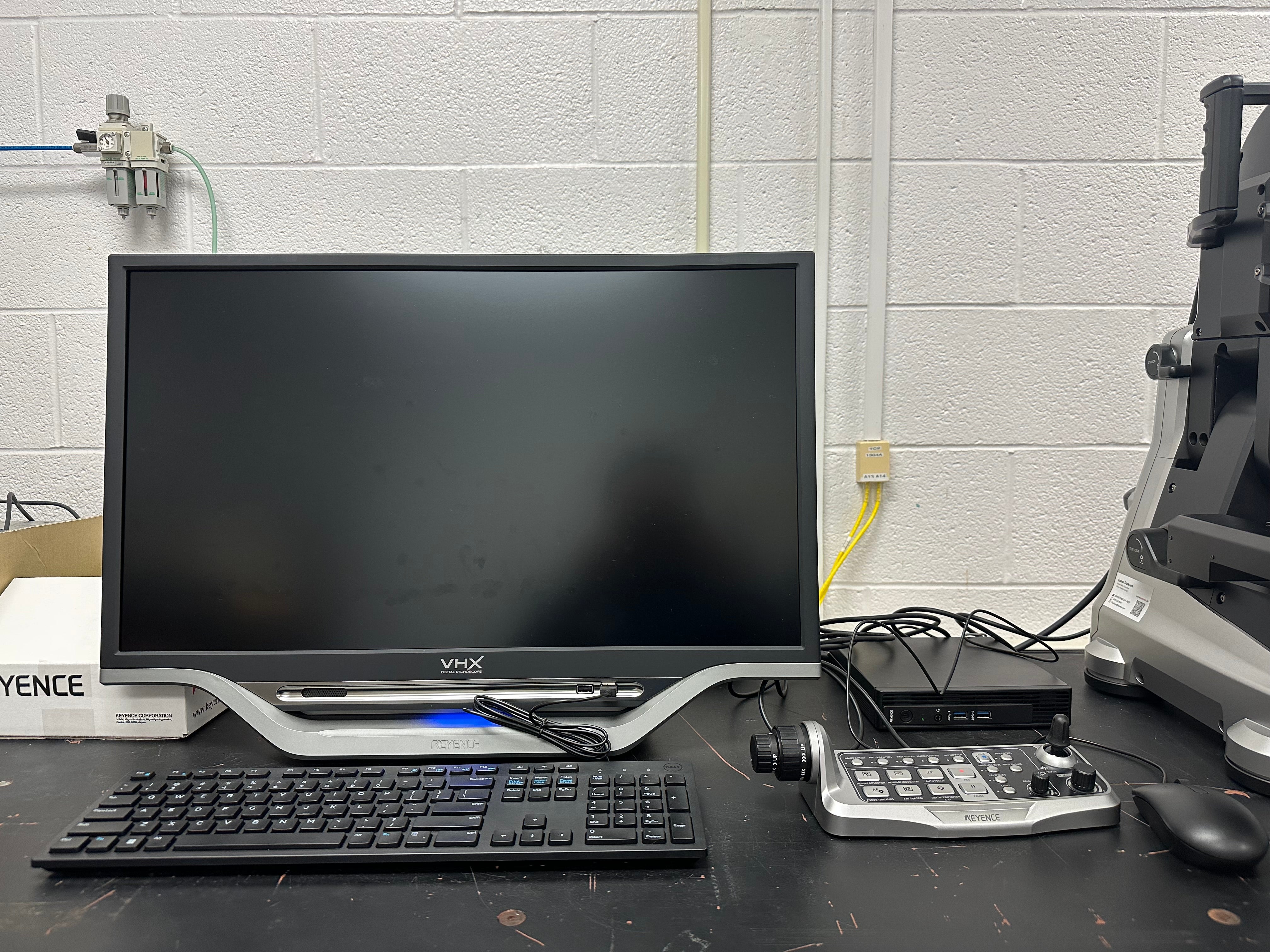 An all-in-one PC with a monitor connected to a cable box leading to an electronic microscope on the right.