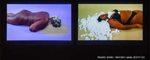 Artwork of two videos projected in a dark gallery.  Video shows a dark skinned person lying on floor with face covered with rice