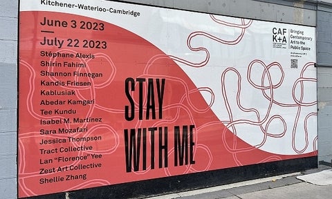 Billboard for CAFKA23; red and white swirl pattern with text in black "Stay with me".