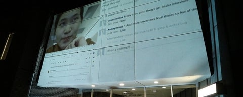 Computer screen projected on a side of a building showing a video of a user and text comments.