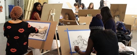Students in an art class seated in a circle and drawing drapery.