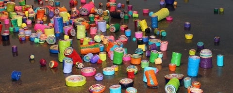 Art gallery floor covered with multiple, multi-coloured, plastic rolls.