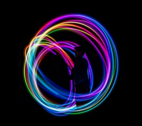 Night photo of a person surrounded by circular swirls of multicoloured light.