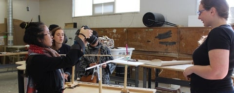Students in an art studio photographing a sculpture.