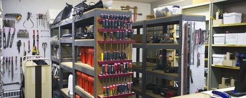 Room with various hardware and tools on shelves and hanging on walls. 