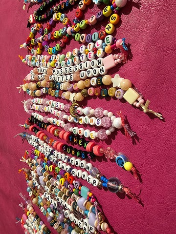 Detail of an artwork featuring stacks of beaded bracelets mounted on a bright pink hide