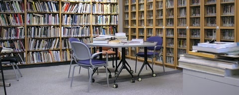 Table and chairs in the middle of a room lined with shelves filled with books.