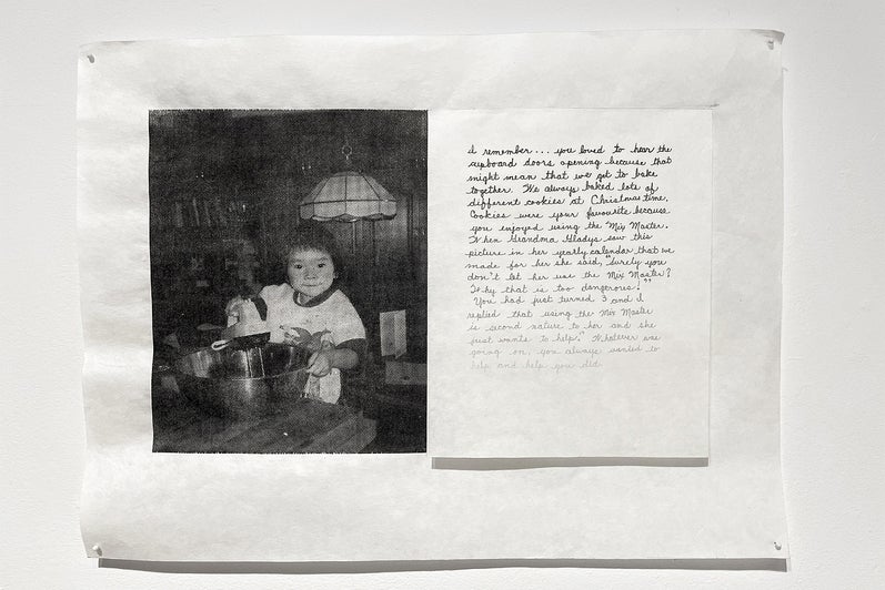 Artwork with a black and white photo of a chid using egg beaters and a handwritten note with ink fading from black to barely vis
