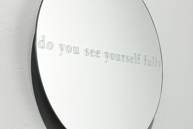 Circular mirror with text "do you see yourself fully" view from the side