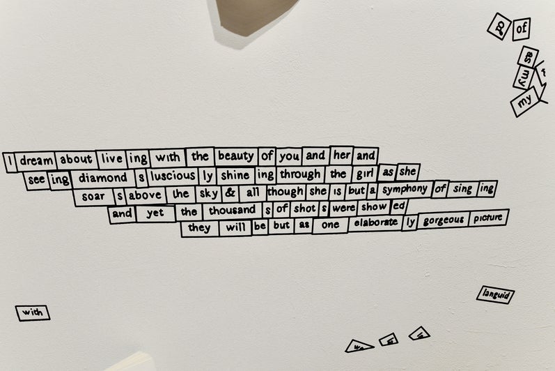 Detail of an art installation showing a vinyl printed text of a wall designed to look like Magnetic Poetry Refrigerator Magnets 