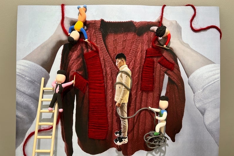 Photographic collage of two hands holding a sweater with wooden toy figures stiching the sweater and wrapping the artist in cord