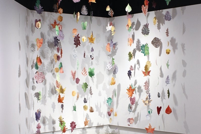 Art installation of multiple strings, hung from the ceiling, of multicolour, leaf shaped, lino prints 