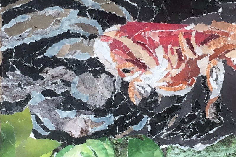 Paper collage of a fish swimming in dark water, green foliage at bottom.