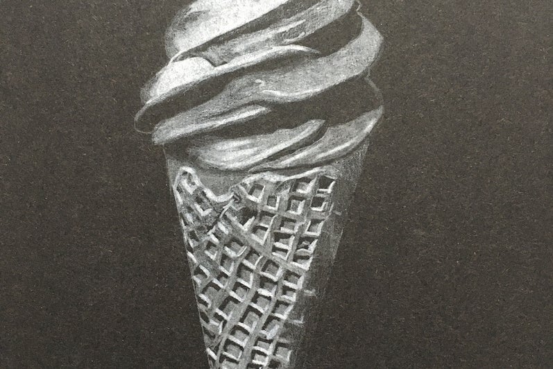 Black and white soft-serve style ice cream in waffle cone, on black background
