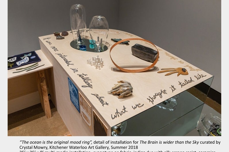 Art installation on table with various glass, ceramic and metal objects. 