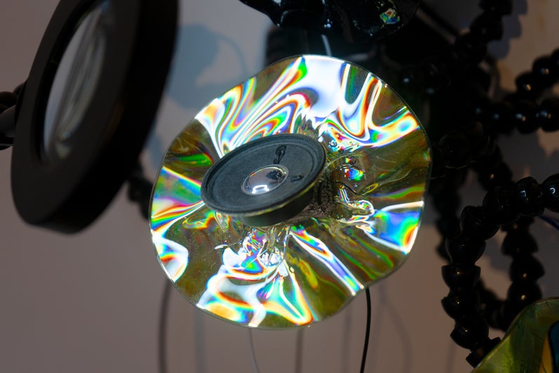 Detail of an digital sculpture with a speaker encircled by a warped CD.