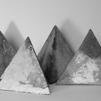 Black and white photo of four small pyramids with rough, irregular surfaces.