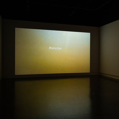 ideo in dark gallery. Video show text "Raincrow" in white against a golden background that brightens to white at top right corne
