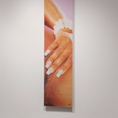 Art exhibition in gallery. Large scale photographs on walls depict details of a black woman's body.