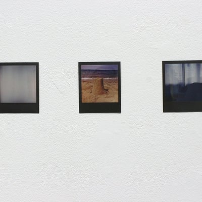 Three polaroid style photos on a wall. Two photos of sheer curtains and one of a sand castle.