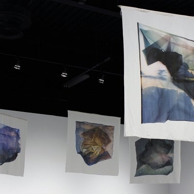 Four banners depicting photographs of sheer fabric overtop of irregularly shaped images of skies.
