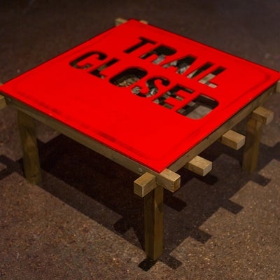 View from above of a low red table, topped with a "Trail closed" sign.