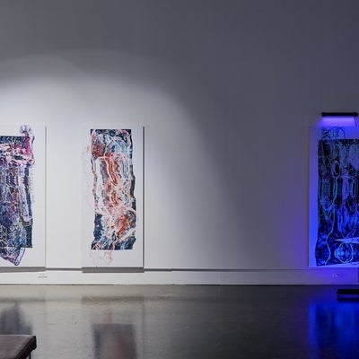 Art gallery installation of three large scale prints of distorted medical scans, one lit by ultraviolet light.