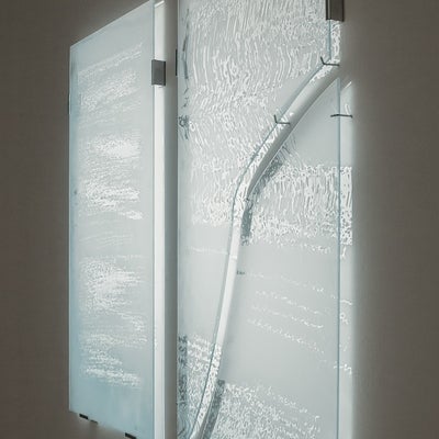 Light is projected onto glass panels, sandblasted with a pattern from medical imaging, which are hung away from the wall causing the light to be shine through.