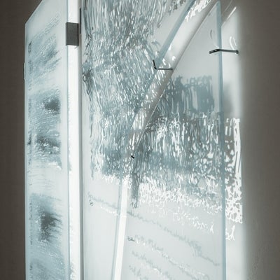 Light is projected onto glass panels, sandblasted with a pattern from medical imaging, which are hung away from the wall causing the light to be shine through.