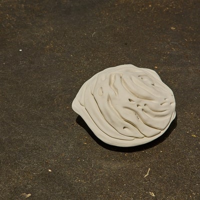 A large off-white porcelain peach pit rests on the floor.