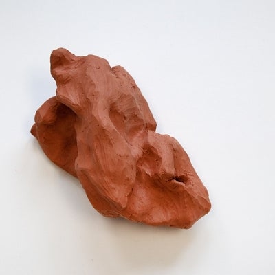Sculpture of red clay molded into a rock-like shape.