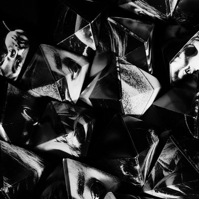 Artwork of a pile of pyramid shapes made from cut and folded black and white portrait photographs.