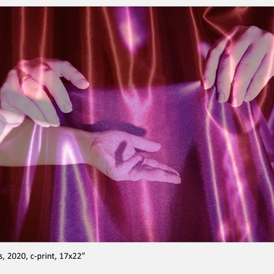 Photograph in shades of red and pink showing three transparent hands against fabric background