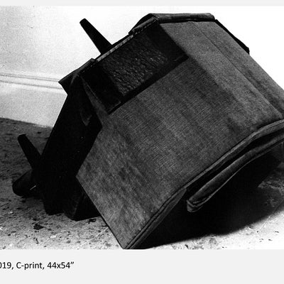 Black and white image of an armchair upside down on the floor