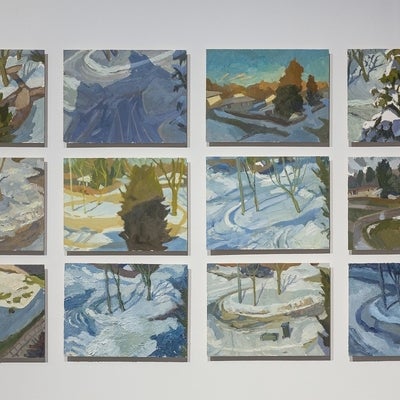 Twelve paintings, hung in a grid, of winter landscapes show views from above of a tree and cul-de-sac.