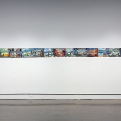 Thirteen small, colourful paintings and hung edge to edge in a line.  The paintings show views of a pedestrian overpass between building. 