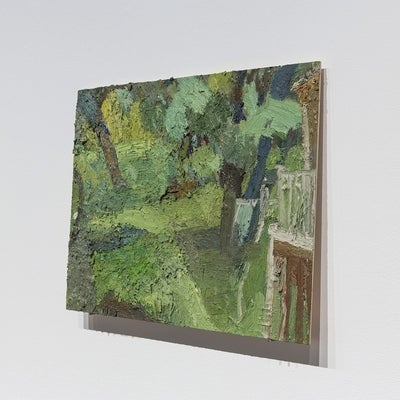 View from the side of a small, thickly painted, tropical landscape. The painting, on thin board, sits on two nails.