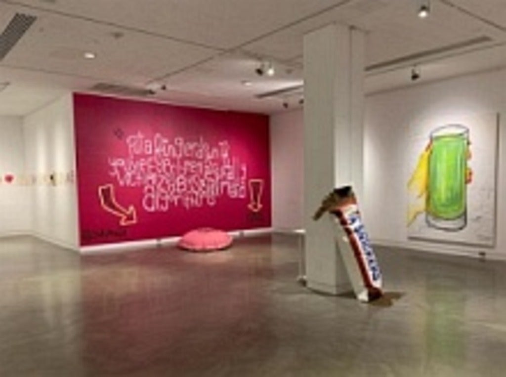 Galley exhibit with large brightly coloured paintings and fabric sculptures on the floor.