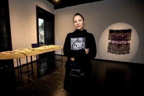 Photo of Katja Kobolt standing in a dark room holding a book