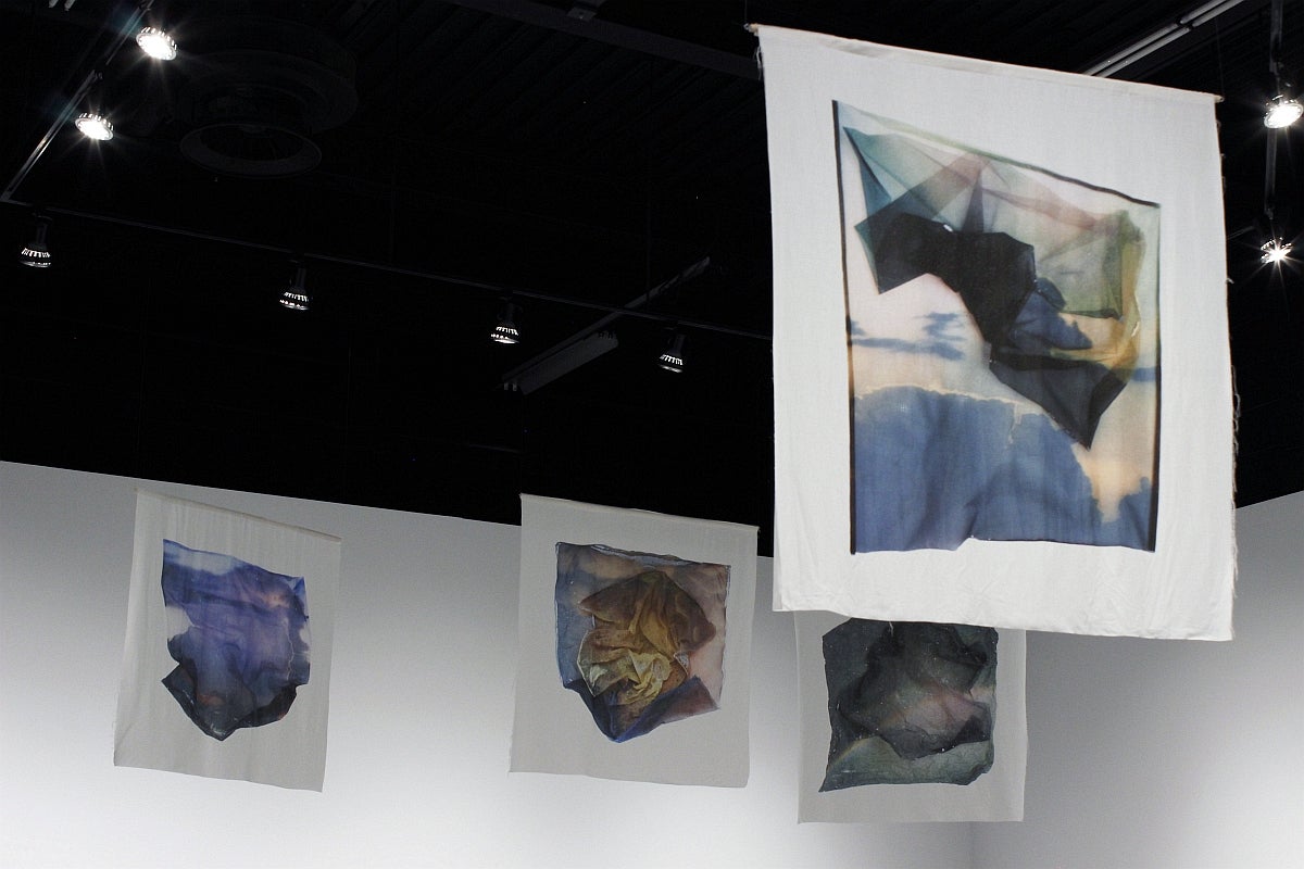 Four banners depicting photographs of sheer fabric overtop of irregularly shaped images of skies.