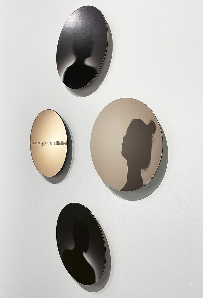 Art installation of 4 circular glass works with woman's portrait in silhouette and text "when perspective is limited"