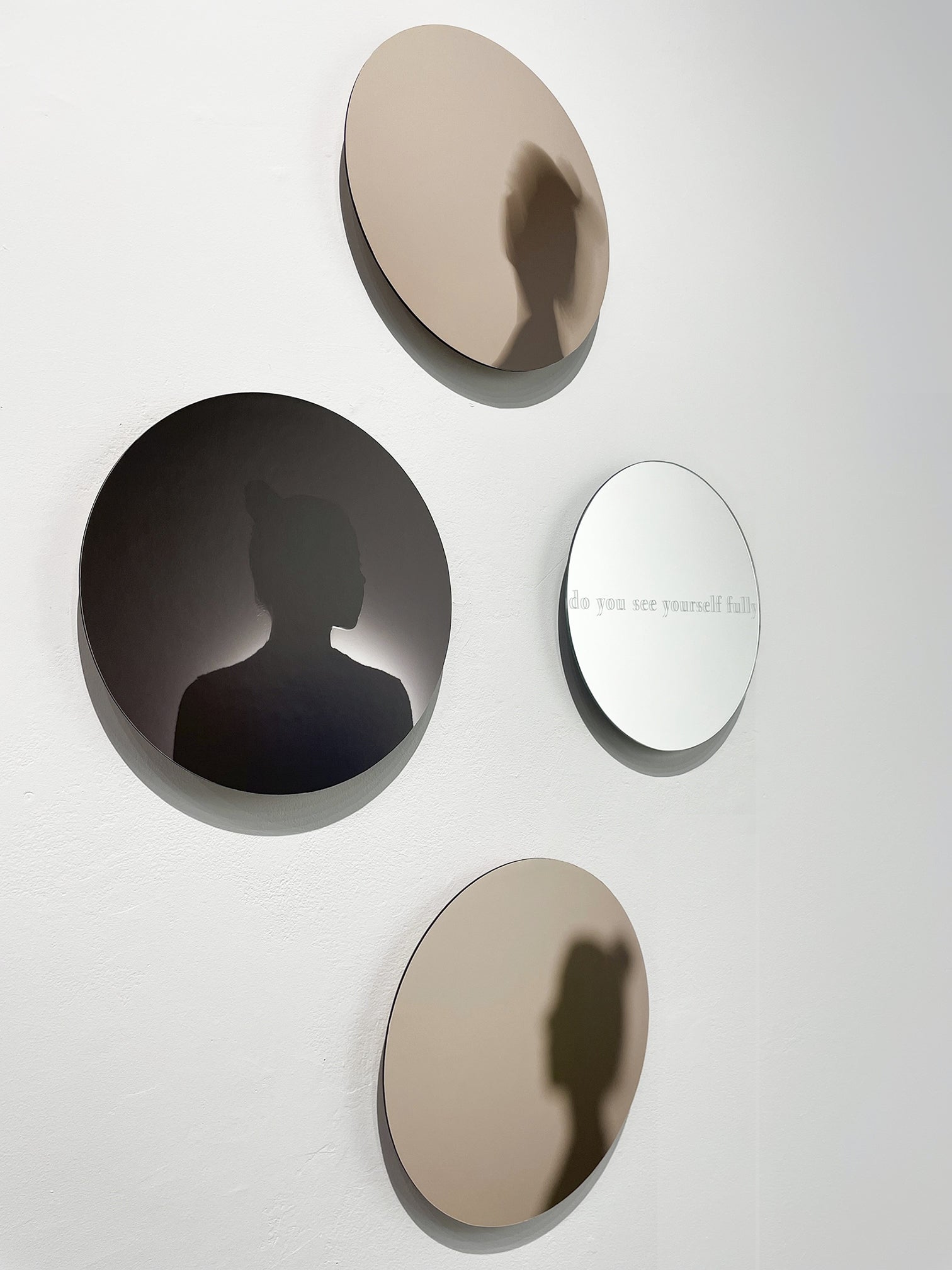 Art installation of 4 circular glass works with woman's portrait in silhouette and text "do you see yourself fully"