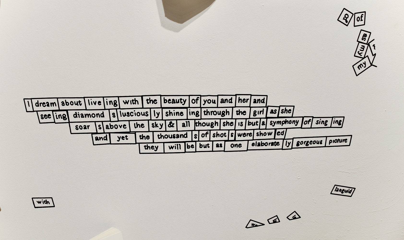 Detail of an art installation showing a vinyl printed text of a wall designed to look like Magnetic Poetry Refrigerator Magnets 